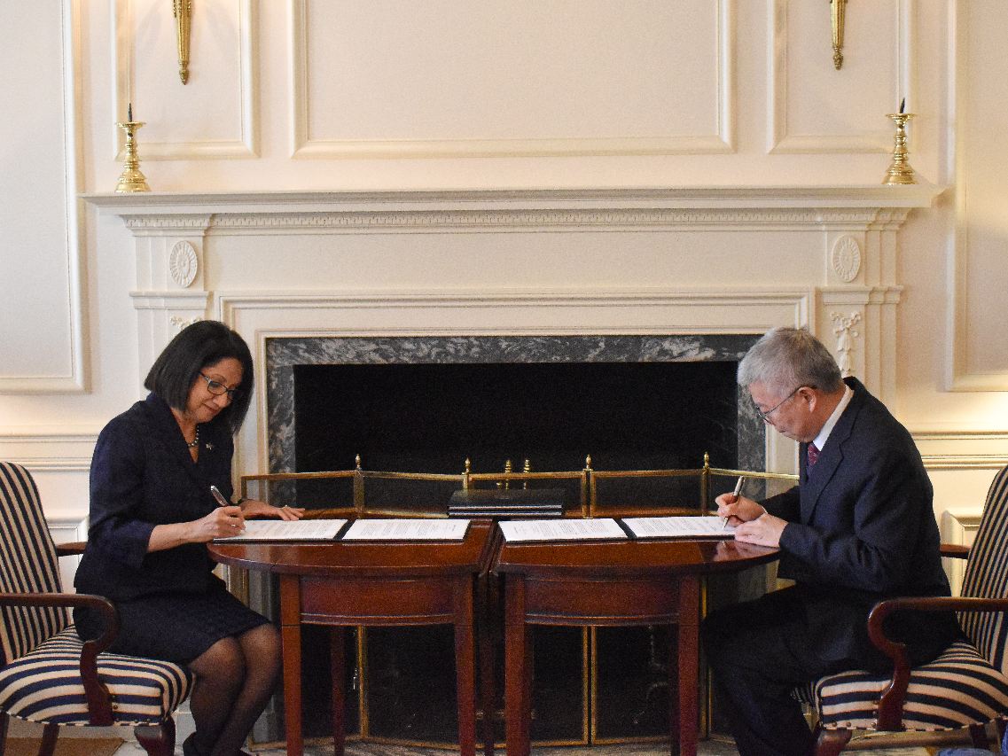 A man and a woman sitting across a table, signing documents