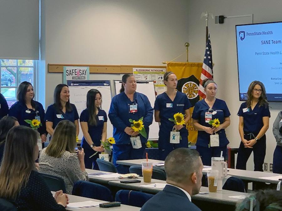 A group of nurses stands at the front of a conference room