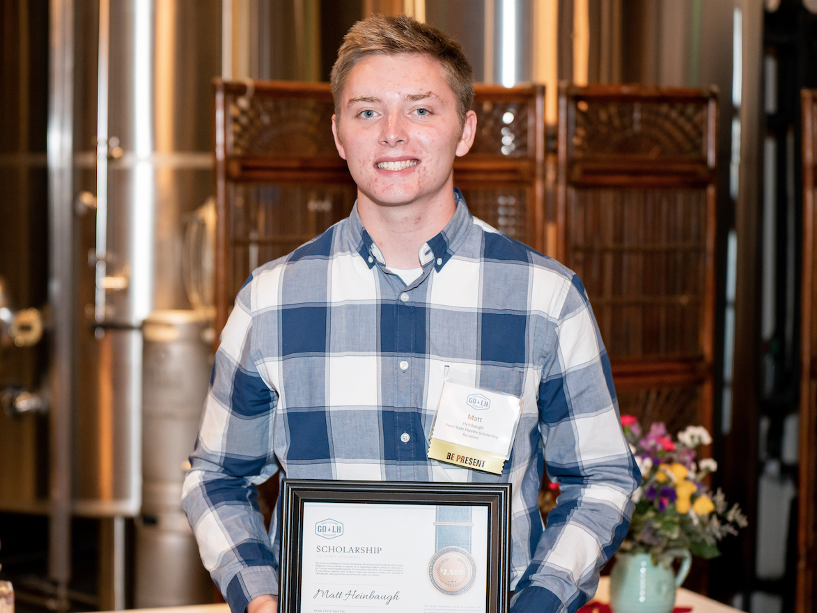 Matthew Heinbaugh holds up a certificate commemorating his scholarship award