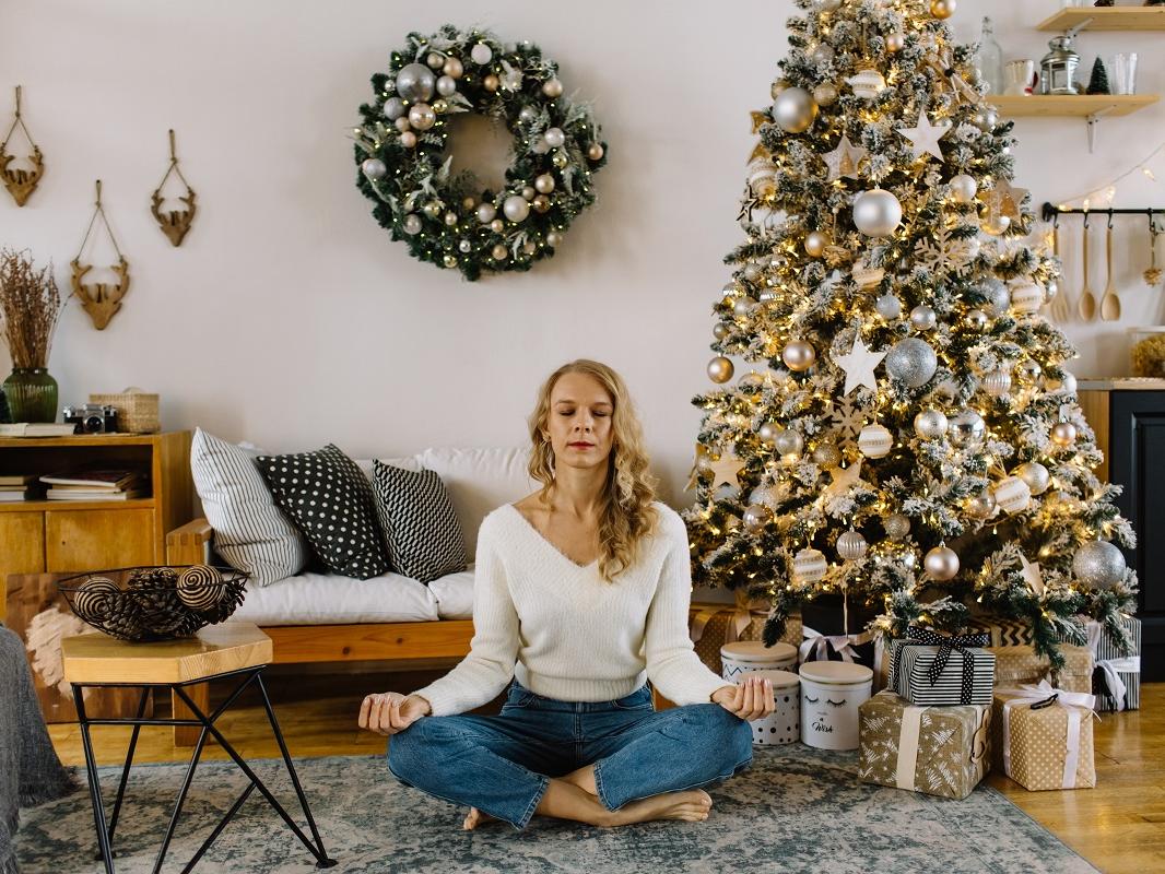 A woman meditates in a home decorated for the holidays.
