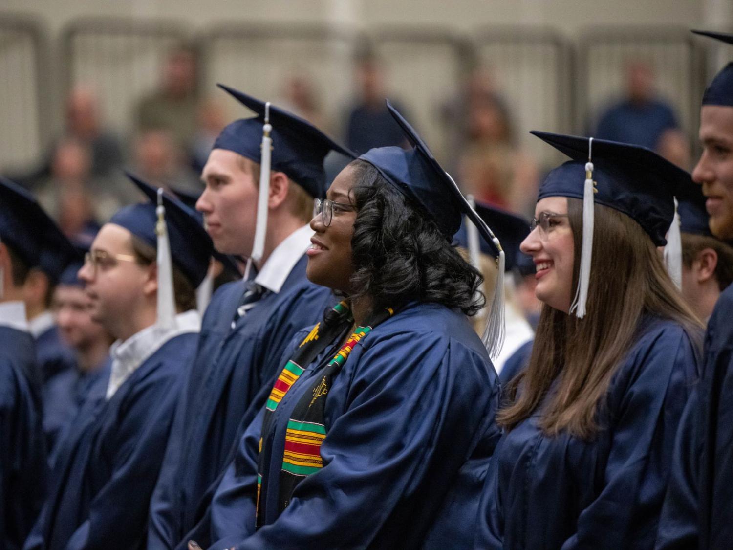 A row of graduates in caps and gowns listen to a speaker during Penn State Behrend's fall 2022 commencement program.