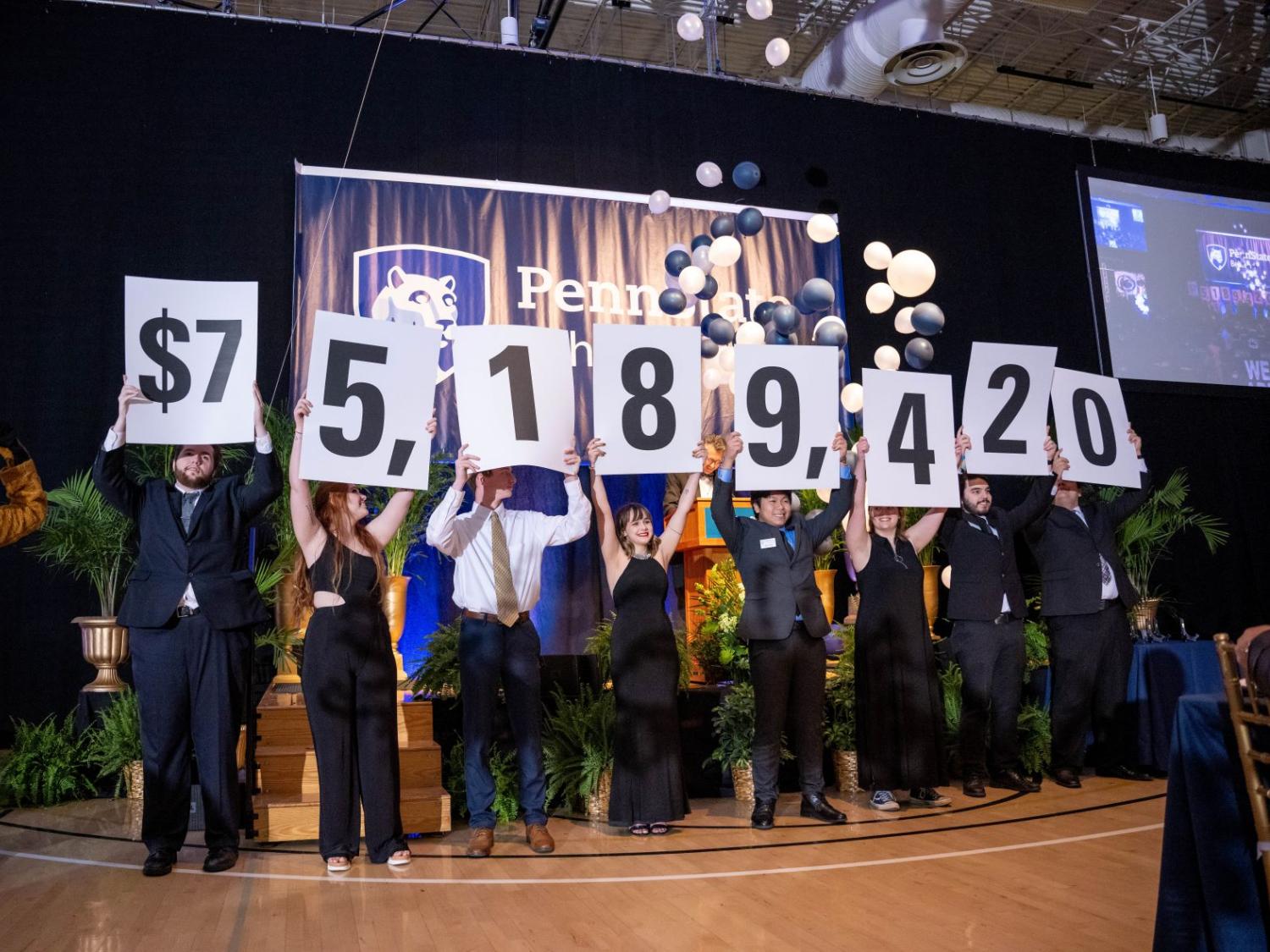 A row of Penn State Behrend students hold up placards with numbers that show the fundraising total in the college's six-year campaign.