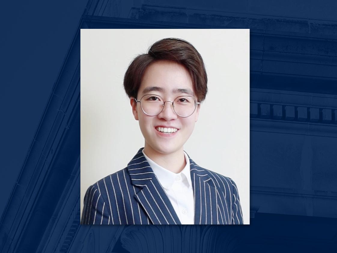 A headshot of a person wearing glasses on a blue background.