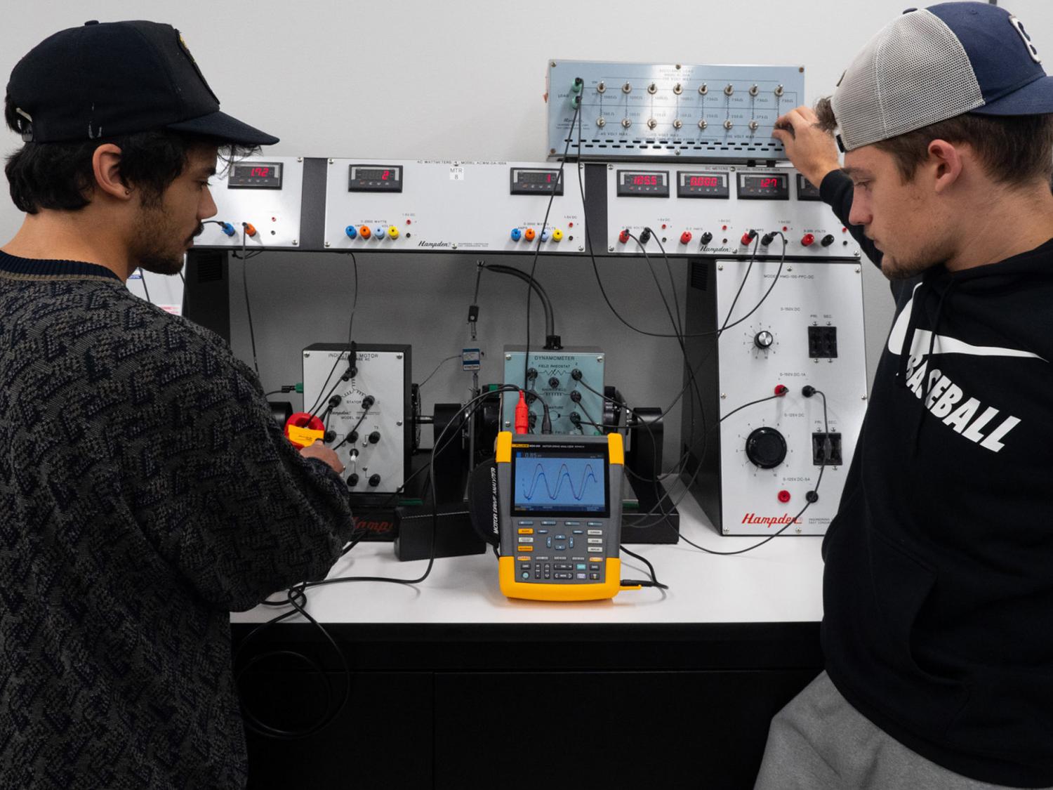 Two students look at a piece of equipment in a lab