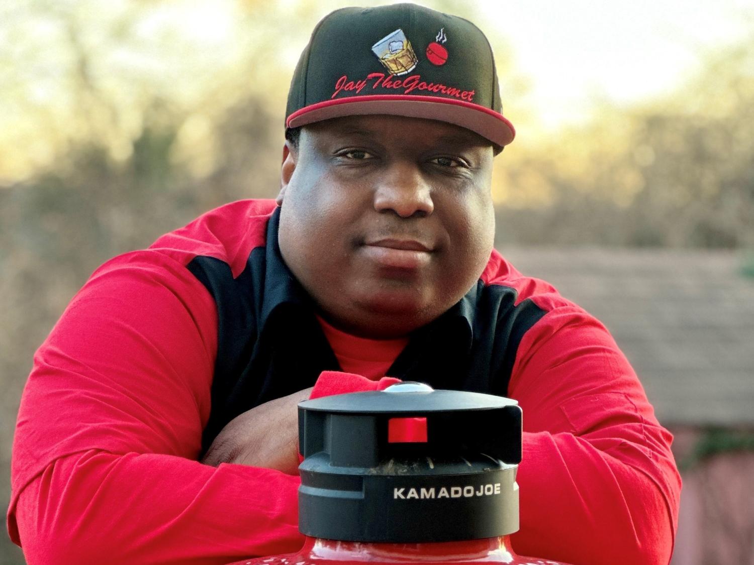 Photo of Joel Gill Jr. posing with a red and black grill