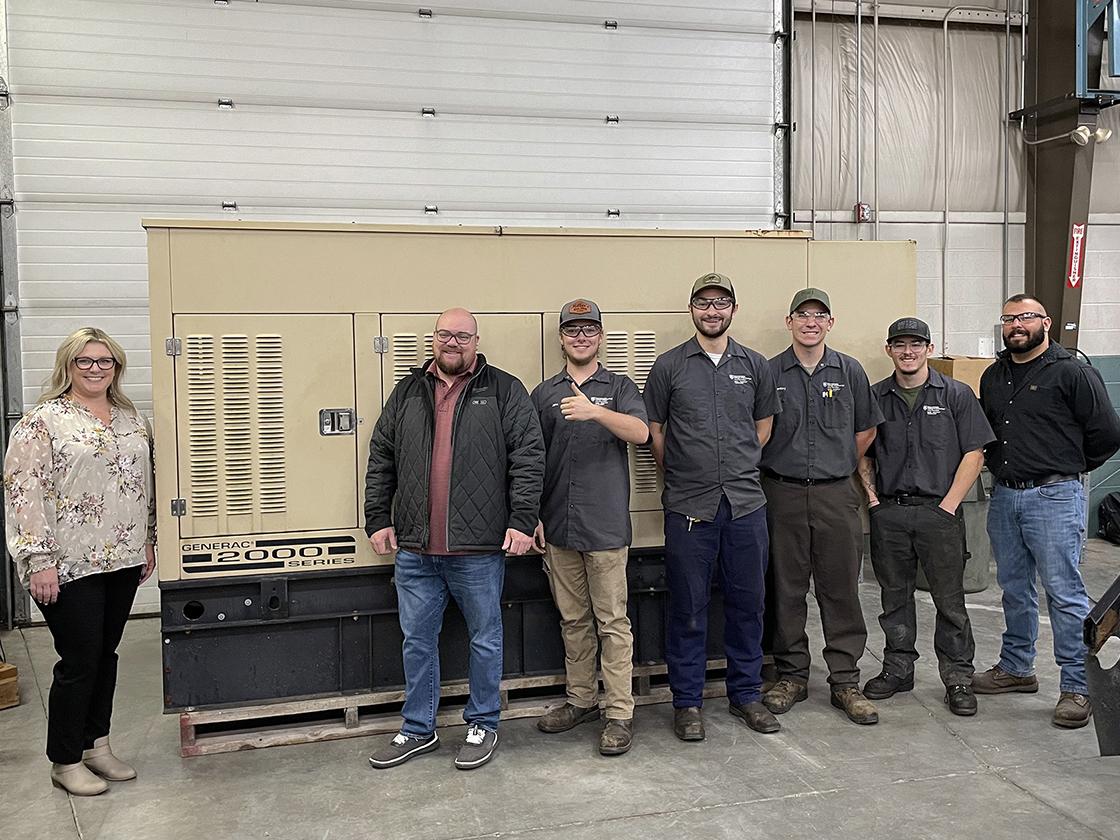 A group of smiling people standing in front of a large piece of equipment