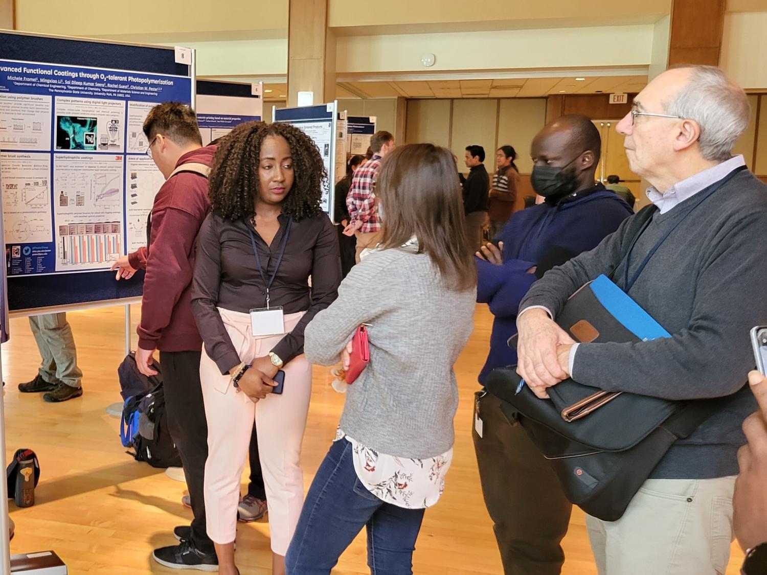 People discussing a scientific poster, including two men and two women.