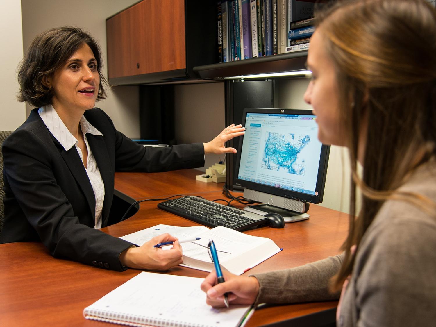A Penn State Behrend professor talks with a student while pointing to a computer monitor.