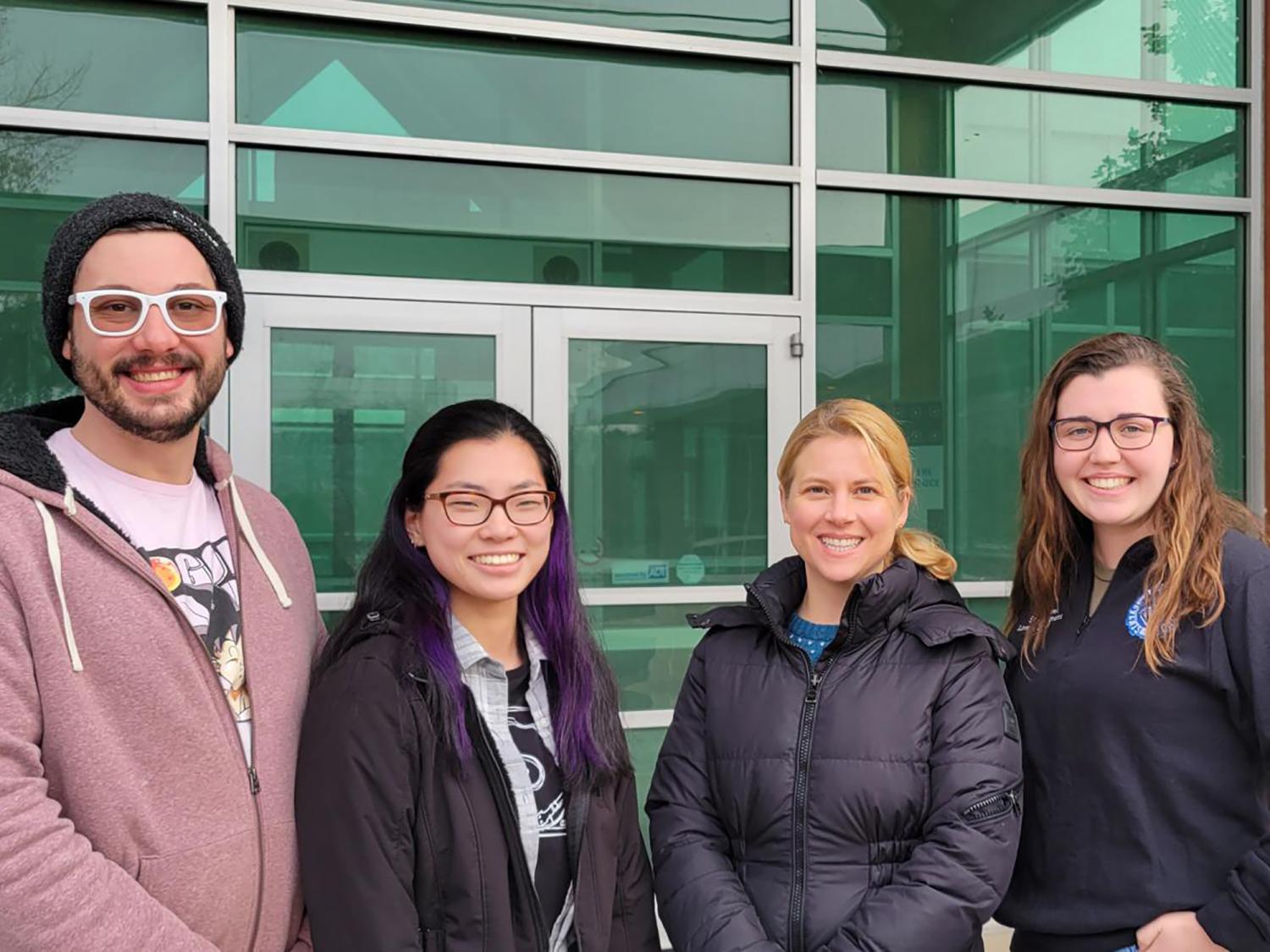 Penn College's four PLNA Foundation scholarship winners stand outside with a glass door and glass wall in the background