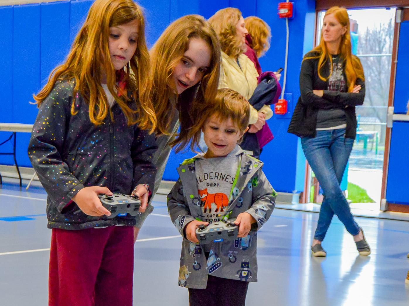 Children at a science festival control robots.