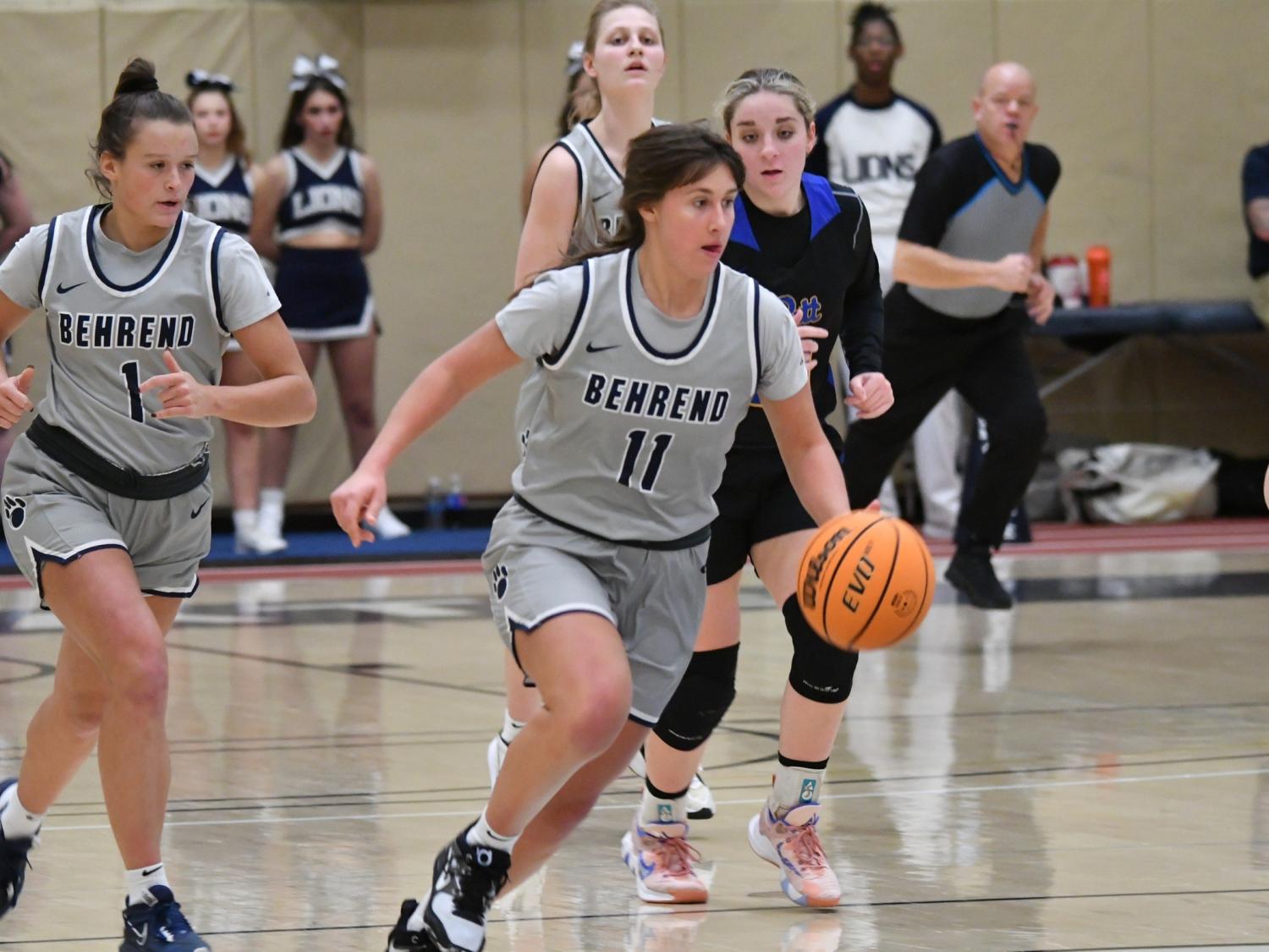 A Penn State Behrend female basketball player dribbles the ball upcourt.