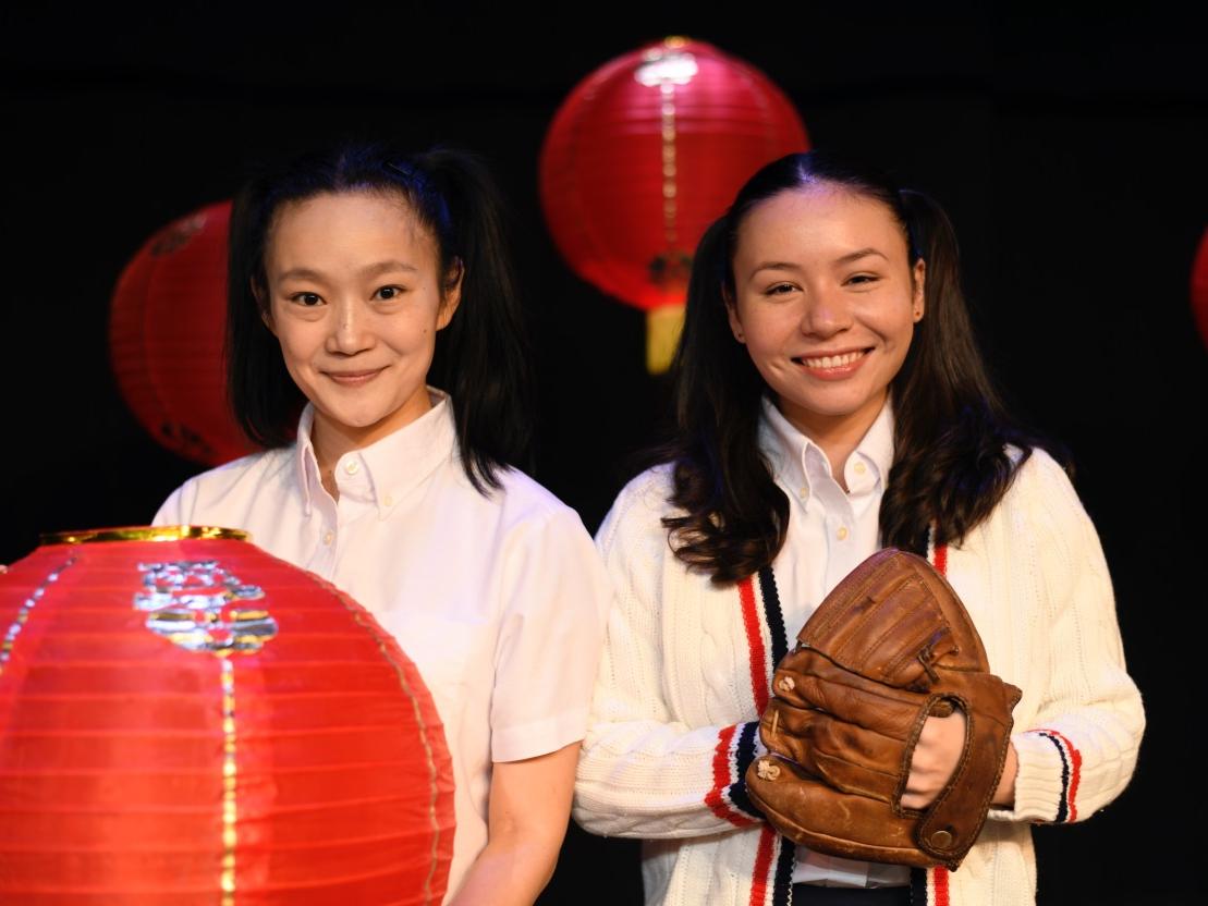 Two girls of Chinese nationality wear pigtails and hold a lantern and a baseball glove.