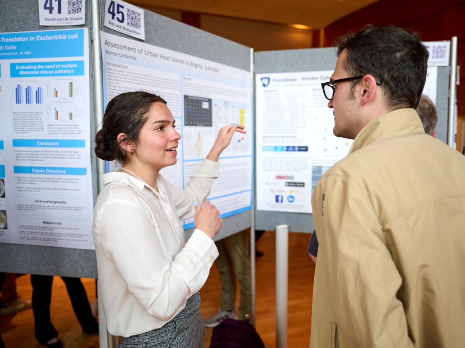 Student explaining her research in front of a poster