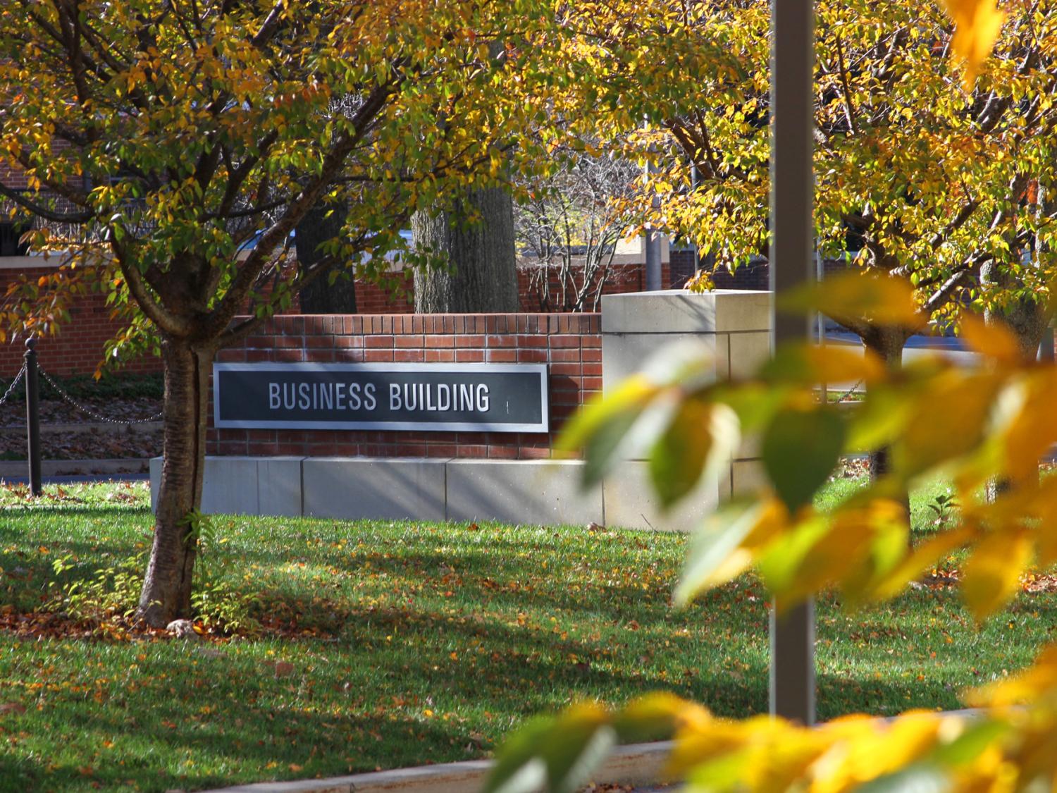 A photo of the Business Building sign framed by trees