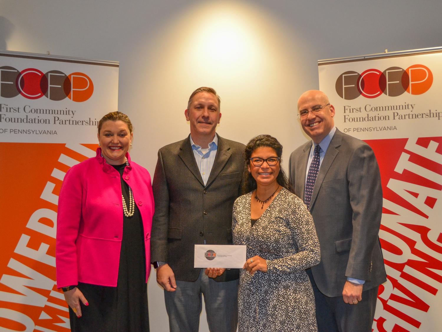A group of individuals stand together holding an envelope