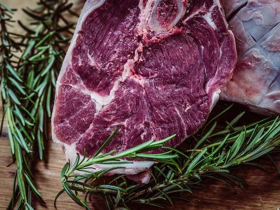 Raw steak resting on a cutting board next to sprigs of rosemary