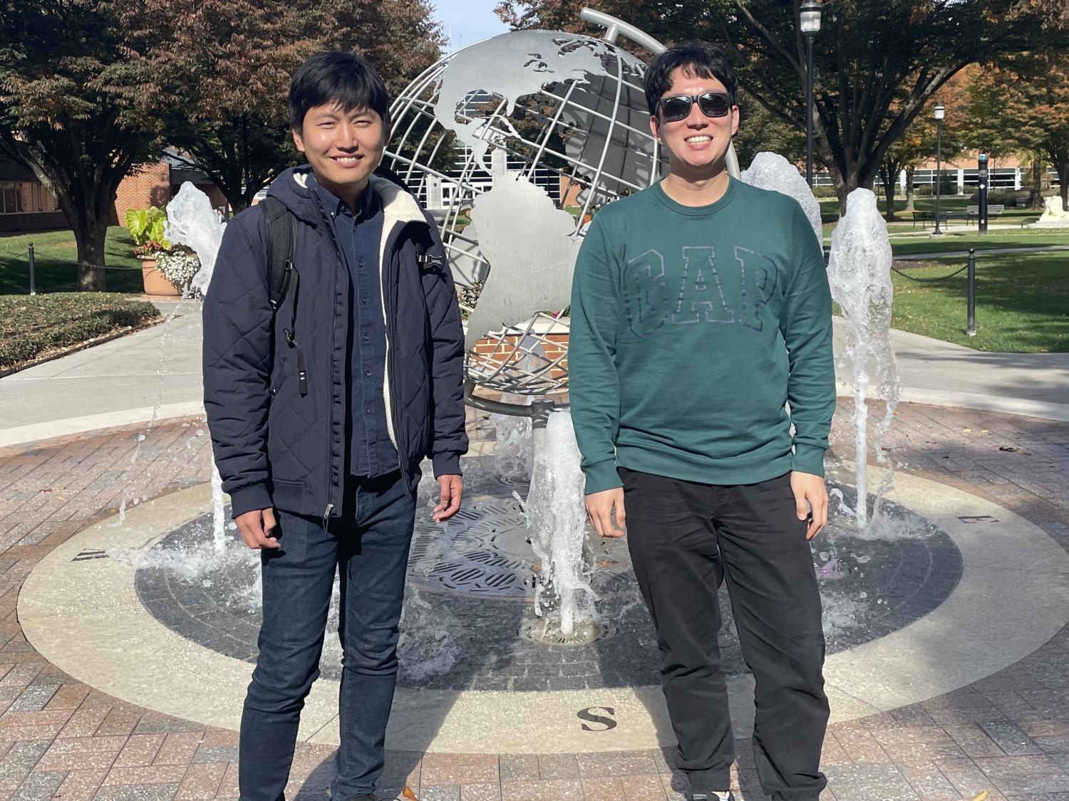 Two men standing in front of a globe statue