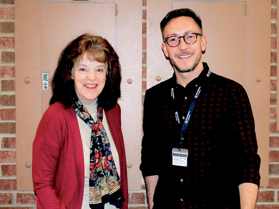 Eileen Giovagnoli and Matthew Smith stand together for a photo in the Study Learning Center with a brick wall behind them in the background