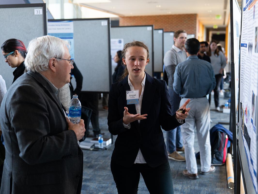 Graduate student explains her research to Raymond Hohl, director of Penn State Cancer Institute, during the Cancer Research Day