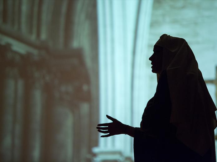 Shadow profile of nun with a projected backdrop of a church