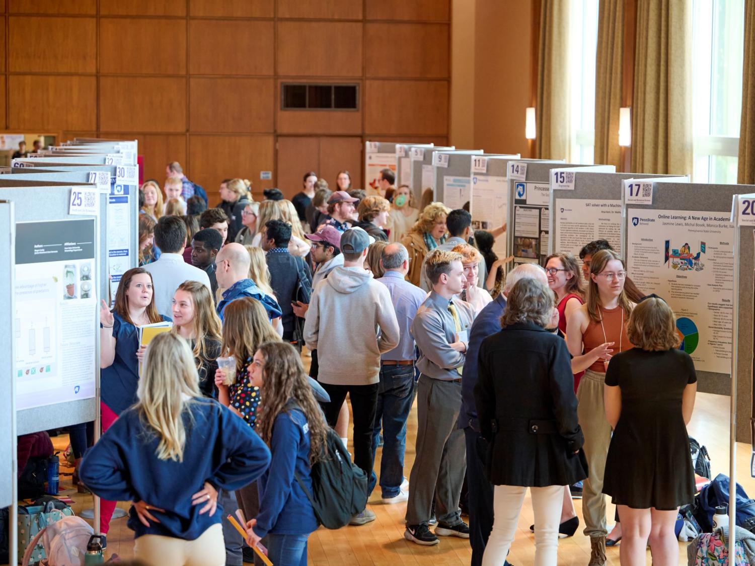 People mingling among research posters at the Undergraduate Exhibition