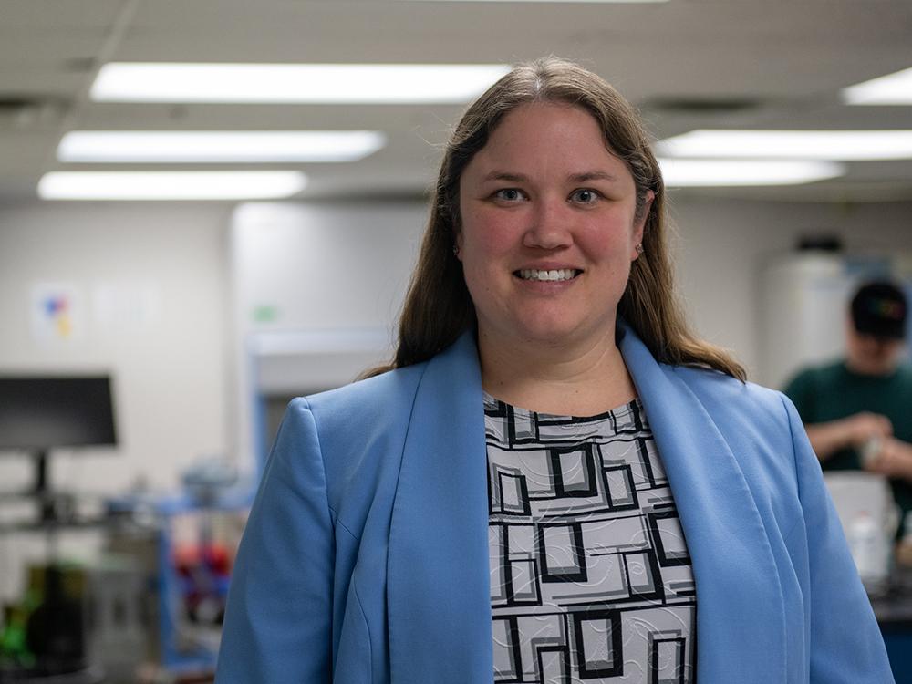 A person in a light blue blazer smiles at the camera