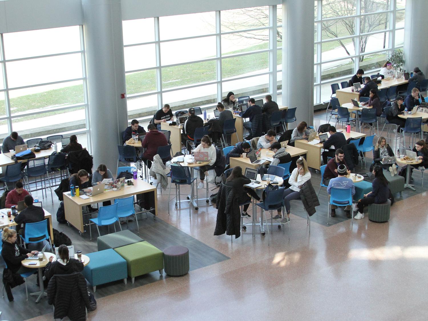 A shot from above of students sitting at tables in the Business Building Atrium.