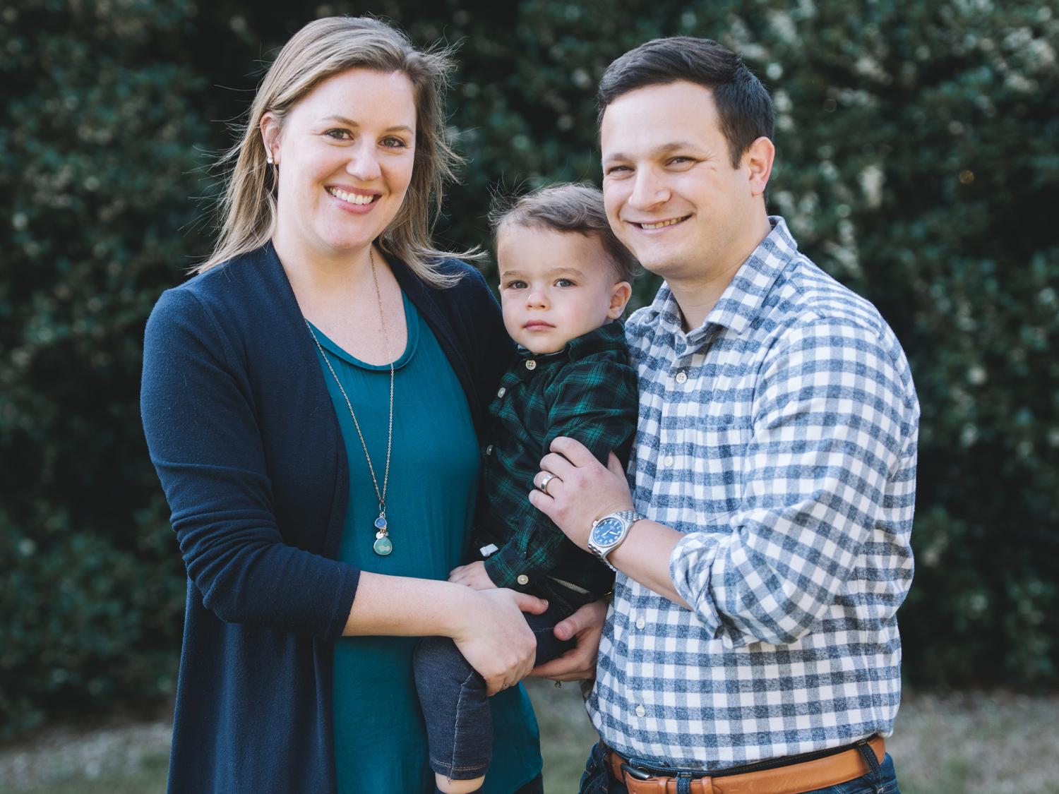 blair kraus denkin and ben denkin posing for a photo while holding their child
