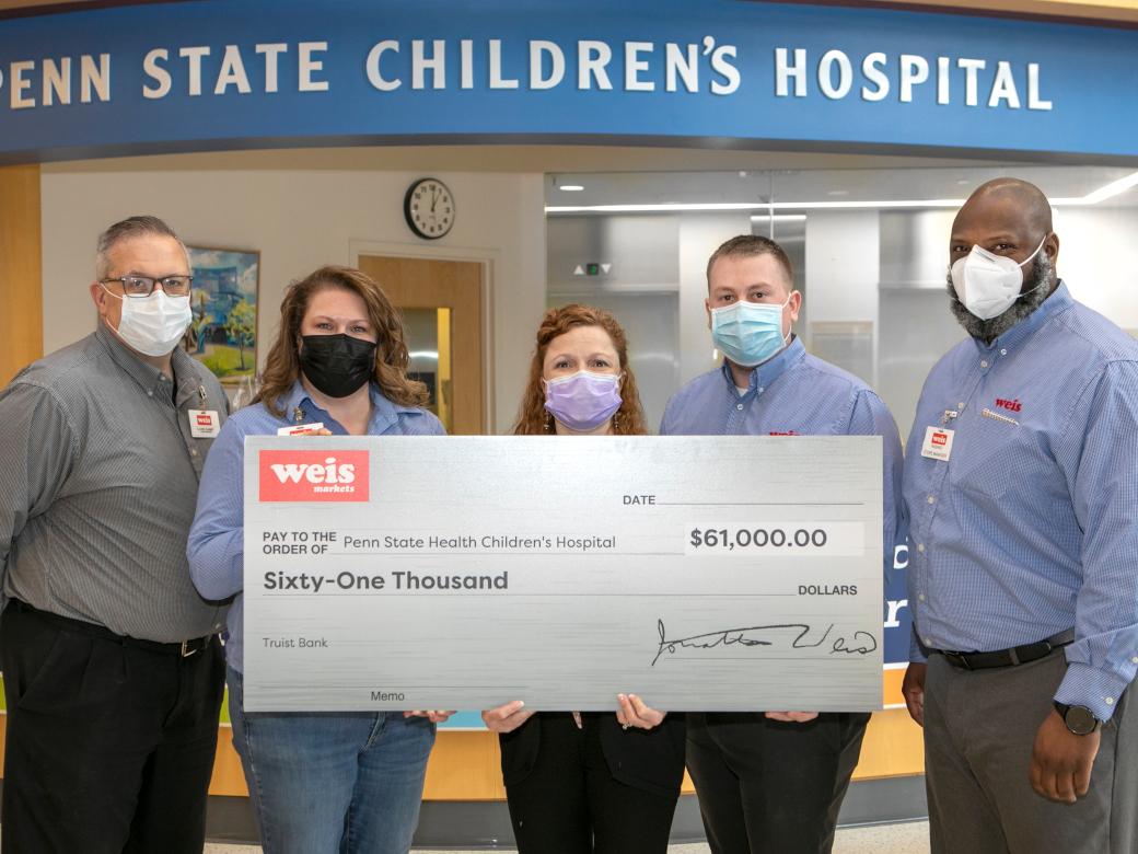 A group of people pose for a photo with a big check