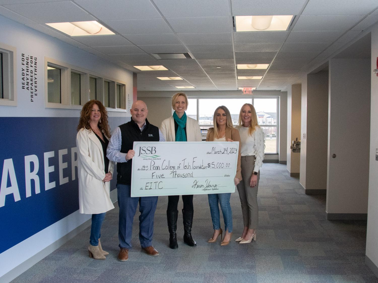 Picture of bank representatives stand with Penn College staff member holding a check.