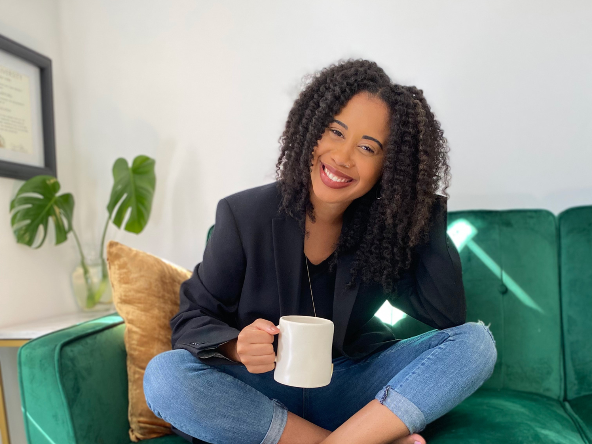 Kenya Crawford poses for an image holding a coffee mug sitting on a couch