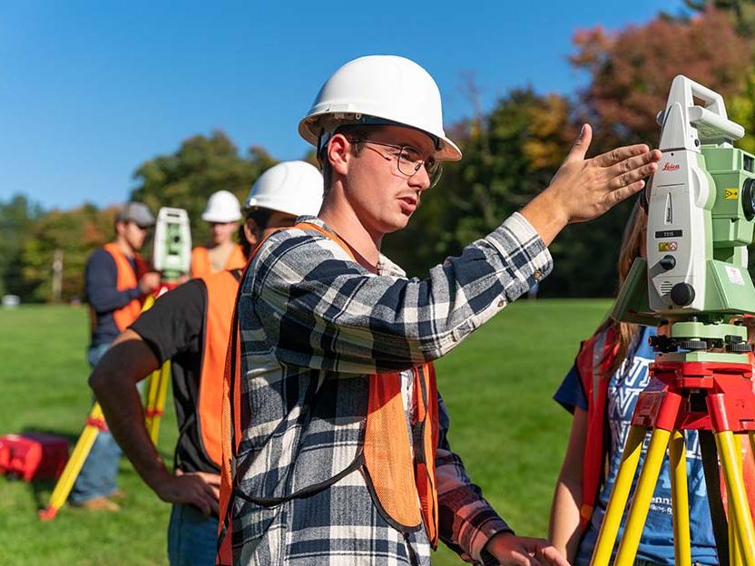 A student working with surveying equipment outdoors
