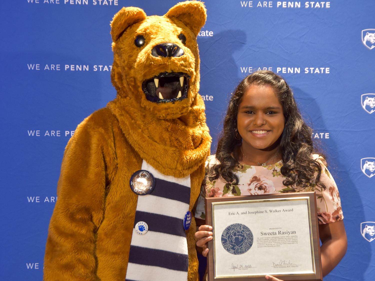 Penn State Nittany Lion and female student pose with award
