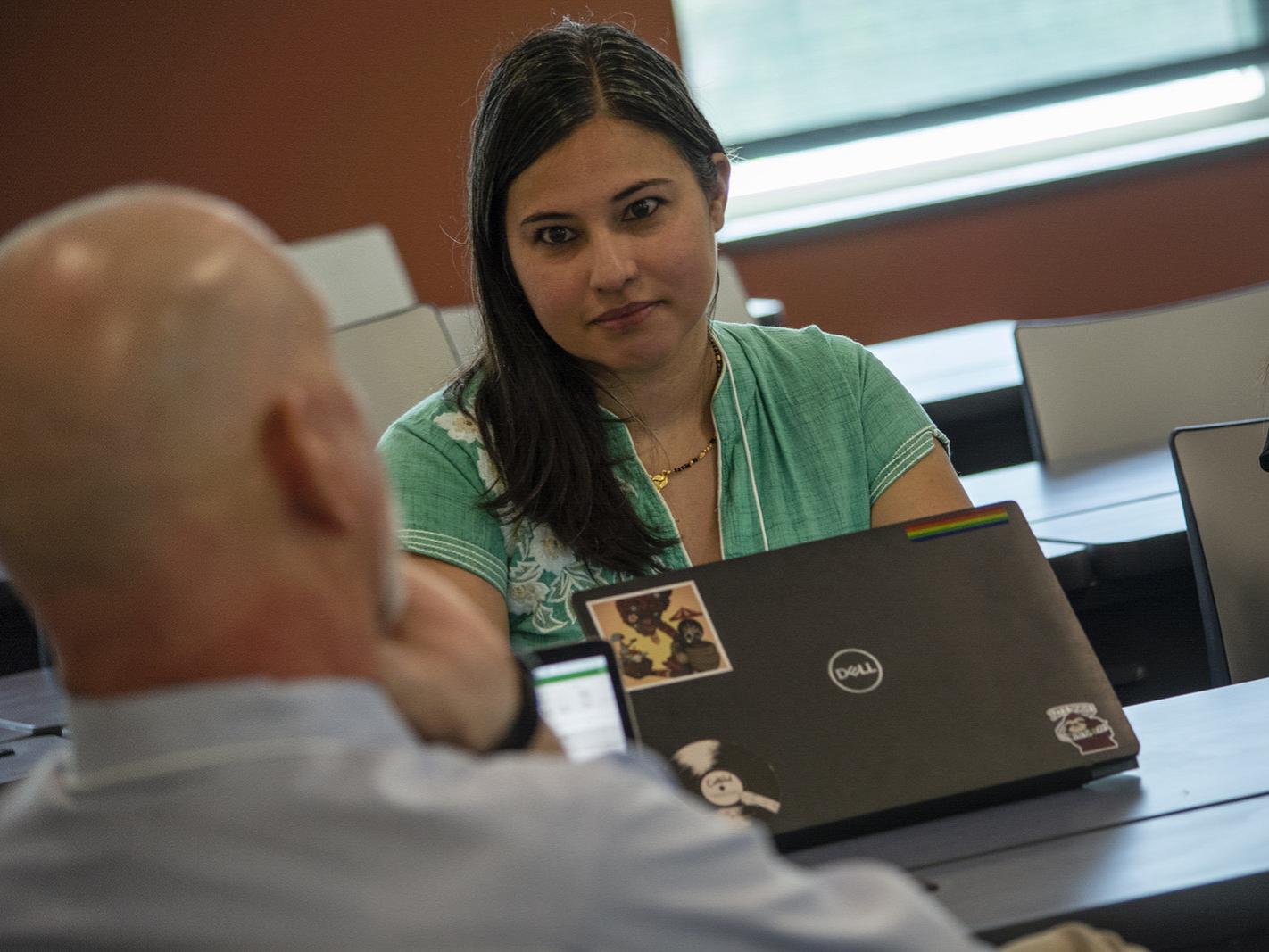Person seated at conference table talking to others