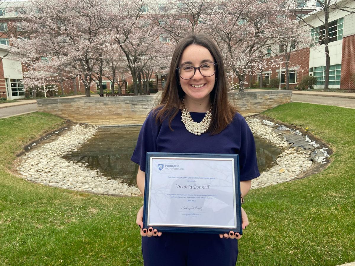 Bonnell stands outside holding plaque