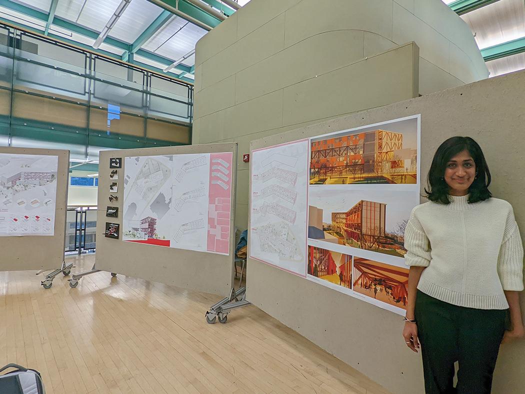 Anjali Gopalakrishnan stands next to pinup boards featuring her architectural renderings.
