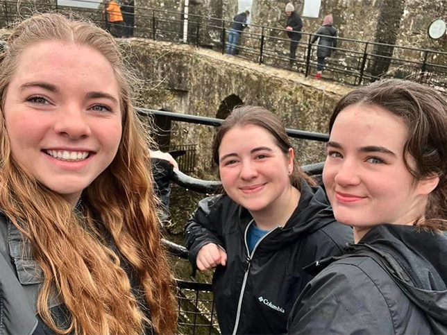 A group of female students stand in a courtyard at Blarney Castle.
