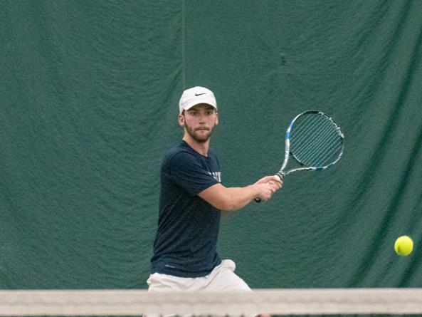 A member of the Penn State Behrend men's tennis team hits a backhand.