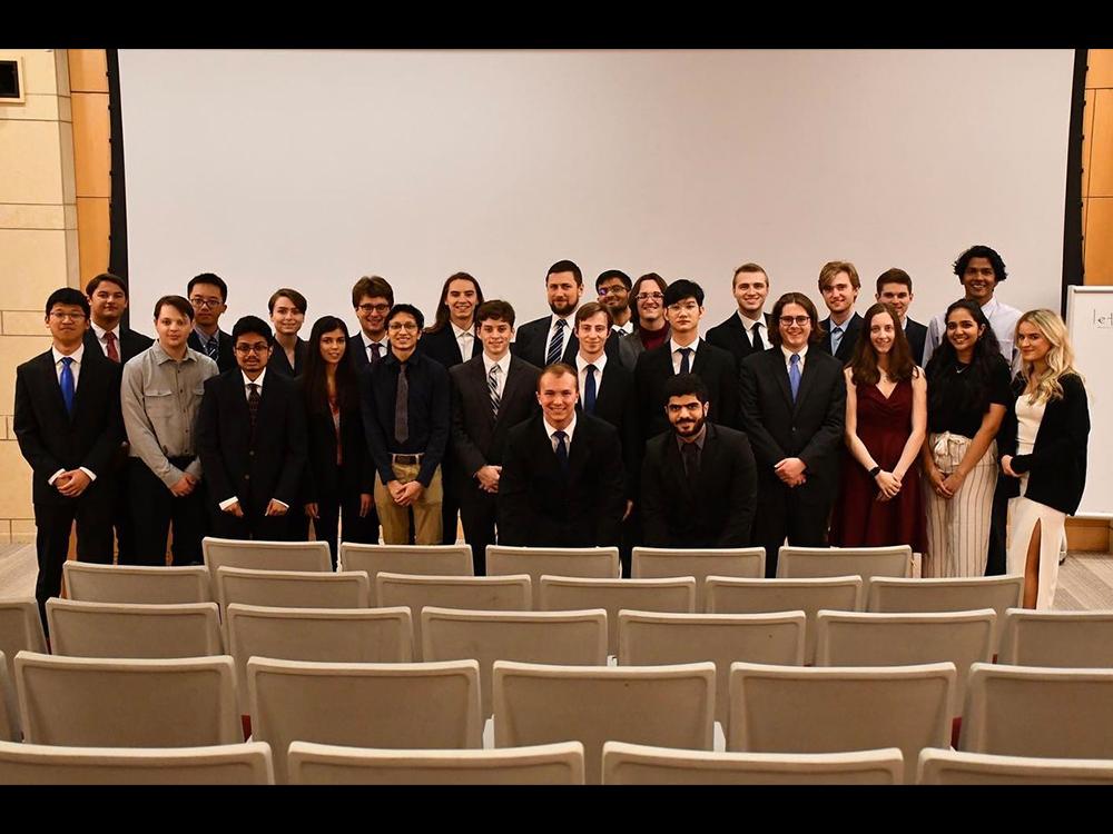 A group of formally dressed students pose in an auditorium. 