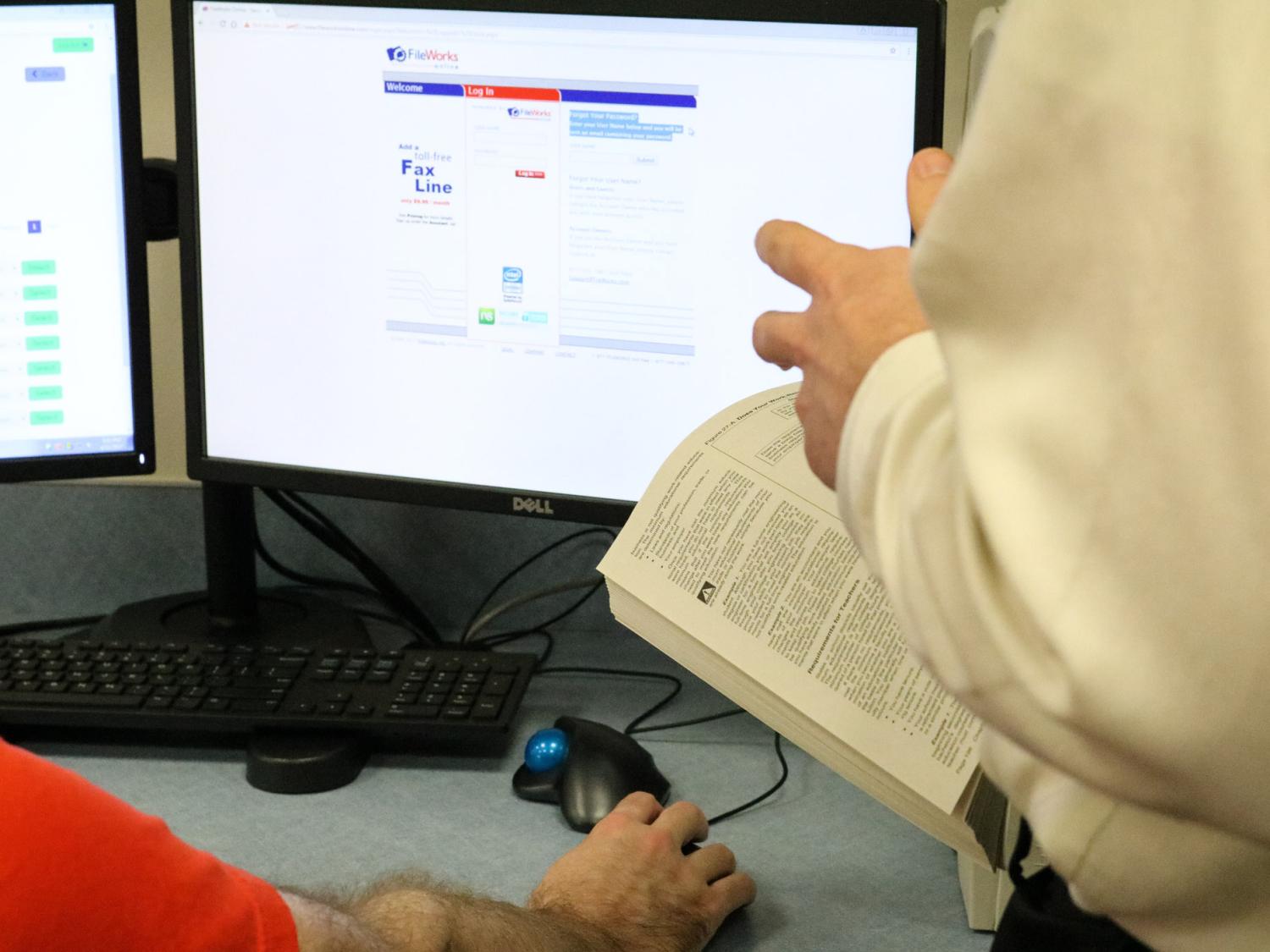 a person holding a book with a computer in the background