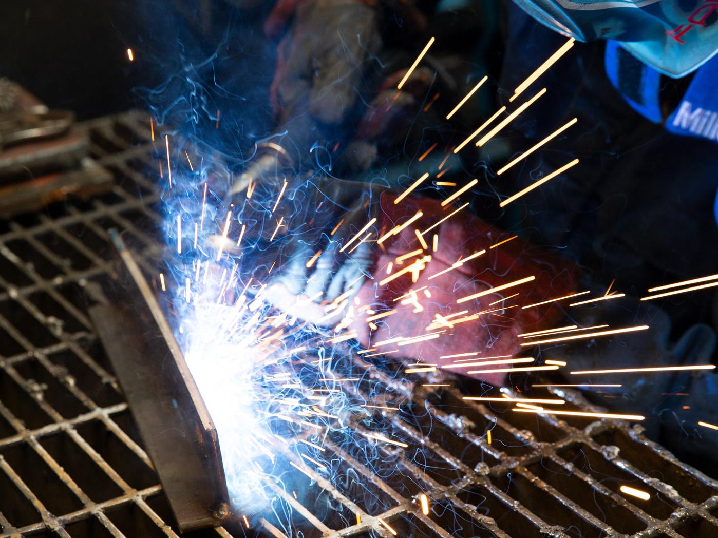 Sparks fly from welding over a metal grate