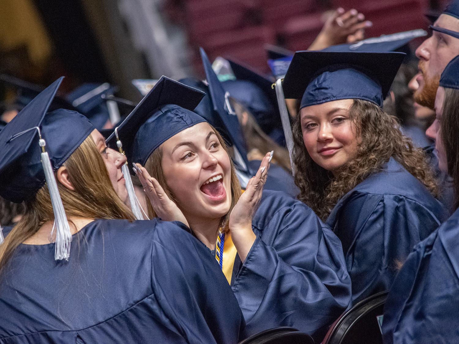 Three women students smiling in caps and gowns at commencement