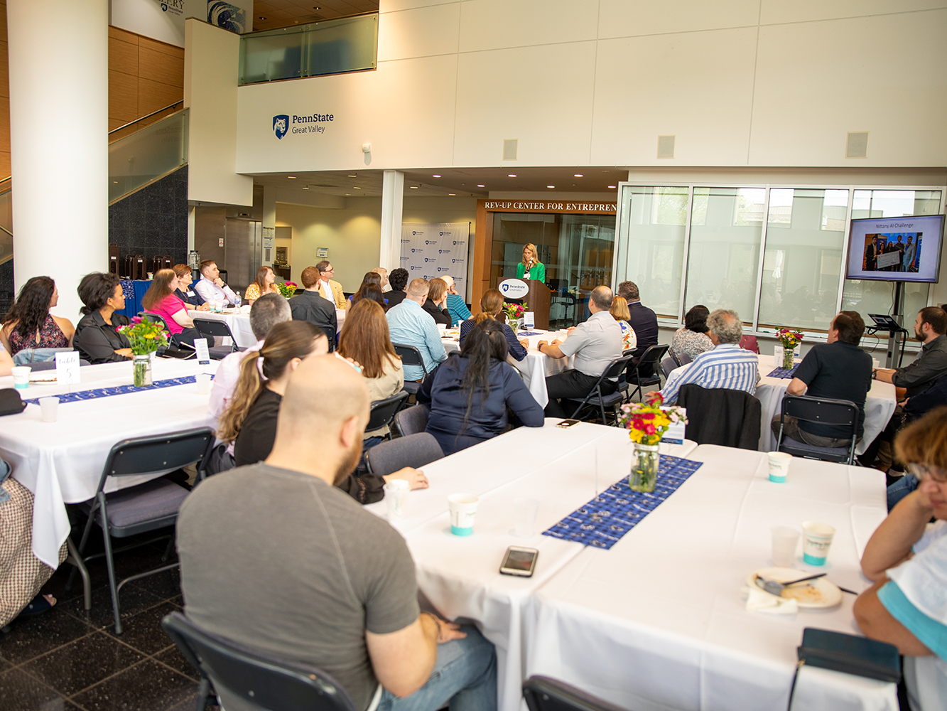 A group of people sitting at tables listening to a speaker