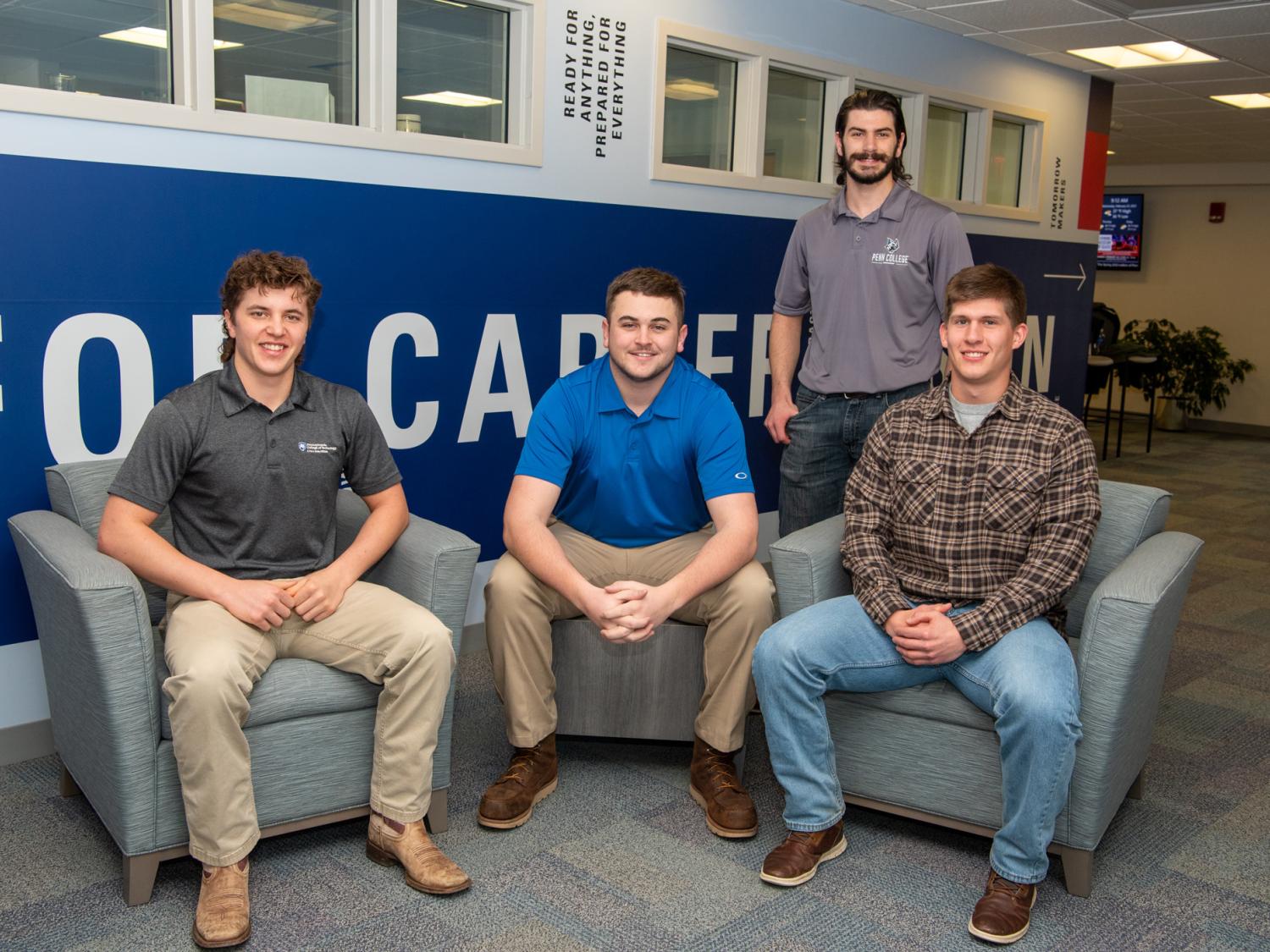 Three students sit and one stands outside of Penn College's Center for Career Design.