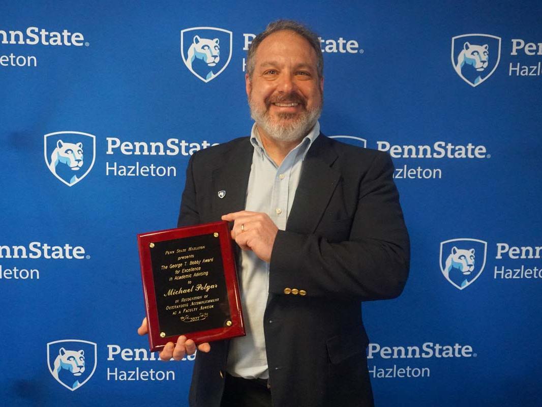Man smiling and holding a plaque.