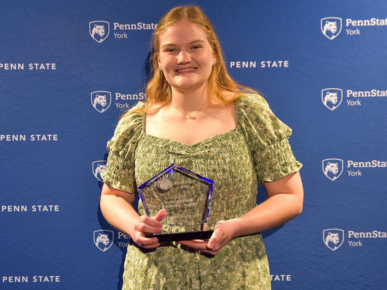 Female student with long blonde hair holding an athletic award.