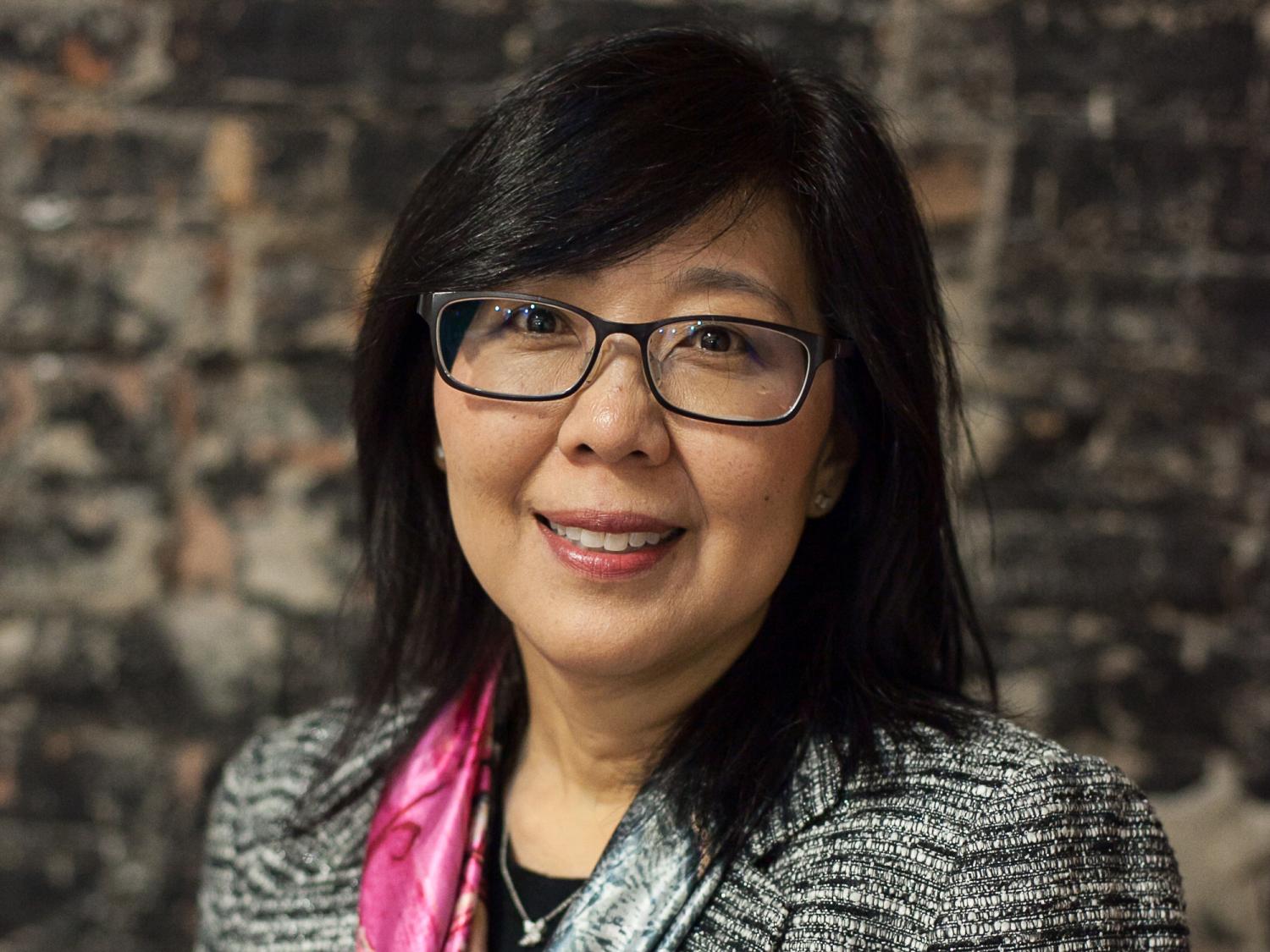 Dr. Karen Kim poses for a photograph in front of a stone wall.