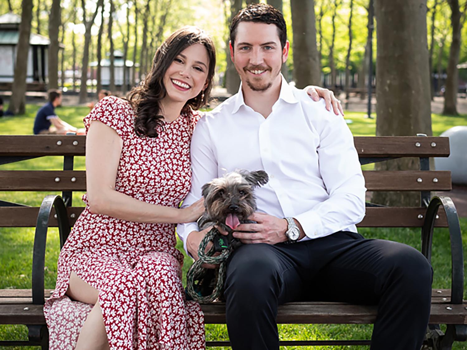 Elana and Robert Messina sitting on a park bench with their dog