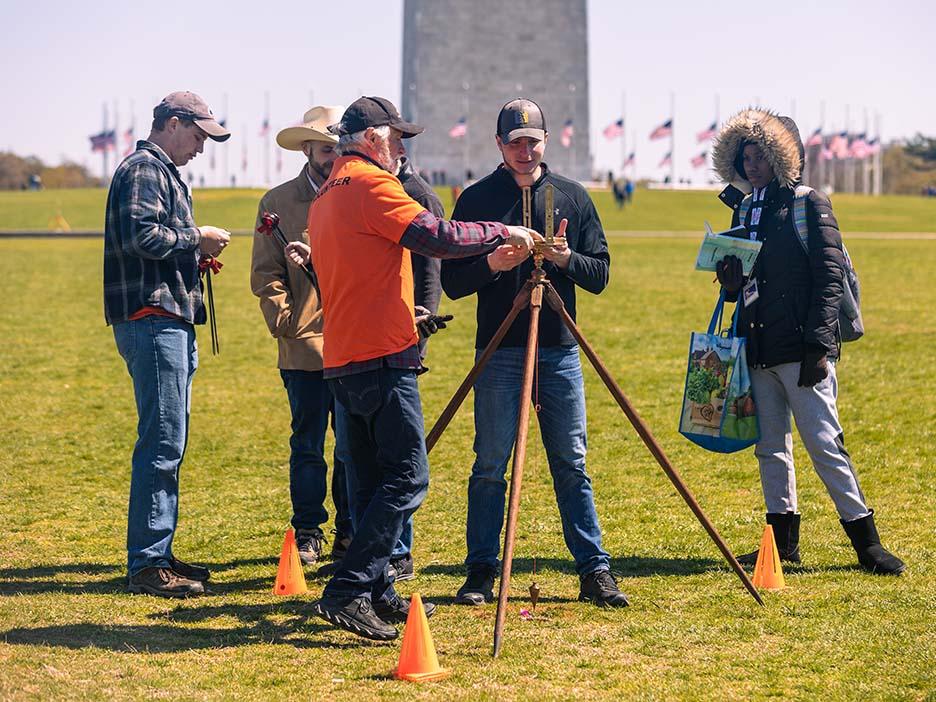 A group of people using surveying equipment outdoors