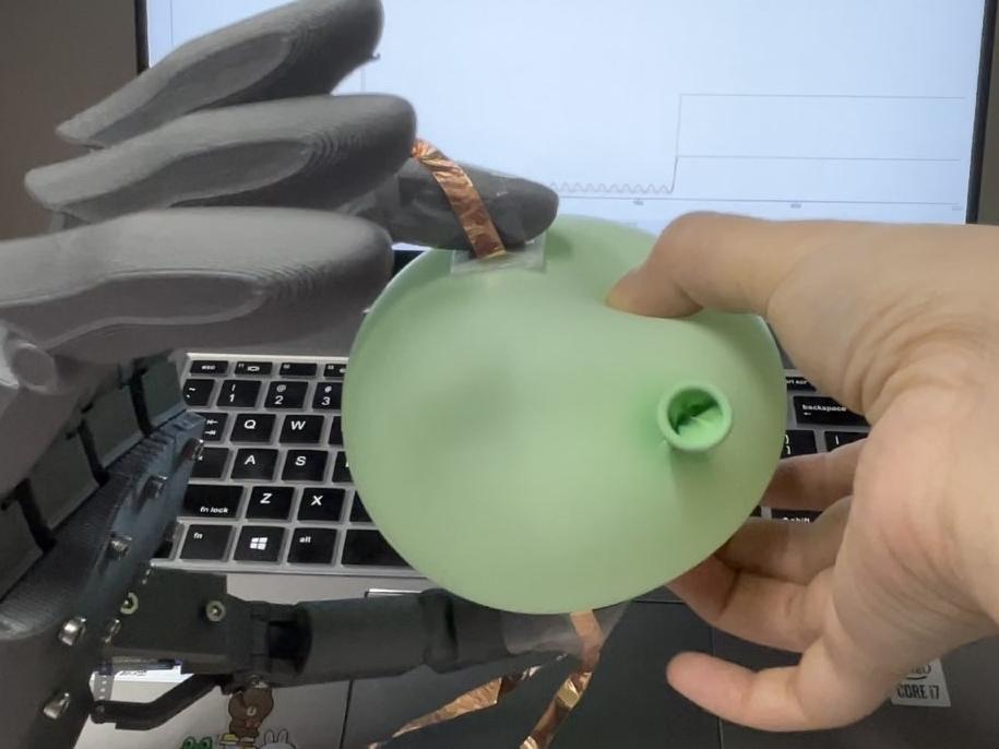 robotic hand squeezing a balloon